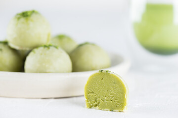Green truffles with matcha and lime on a white table. Sugar, gluten and lactose free and vegan.