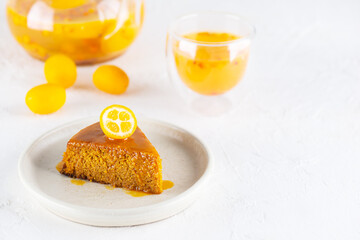 Homemade sea buckthorn cake with orange and kumquat on a plate of tea. Sugar, gluten and lactose free and vegan. Horizontal orientation, copy space.