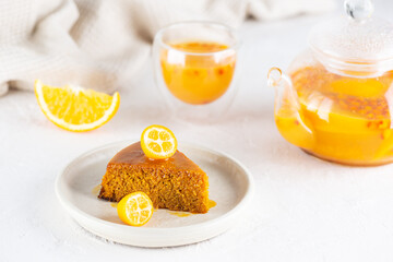 A piece of homemade sea buckthorn pie, mannik with orange, decorated with kumquat with tea. Sugar, gluten and lactose free and vegan.
