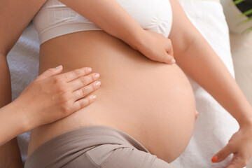 Fototapeta na wymiar Pregnant woman getting massage by therapist in spa salon, closeup