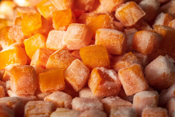 Frozen fresh carrot cube pieces closeup background