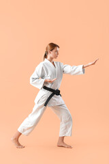Fototapeta na wymiar Young woman practicing karate on color background