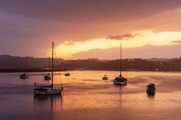 A horizontal shot of a variety of boats sailing on the Knysna lagoon during a magnificent, golden cloudy sunset, Knysna, Western Cape, South Africa