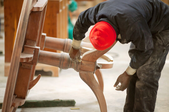 An African male woodworker sanding down a handmade classic table in a furniture factory, Johannesburg, South Africa