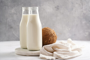 Two bottles with non-dairy milk and coconut on round marble board