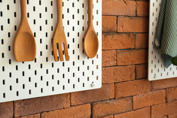 Peg board with wooden spatulas hanging on brick wall