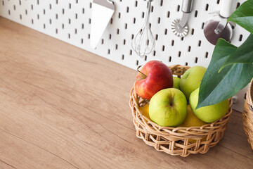 Wicker basket with apples on table top in kitchen