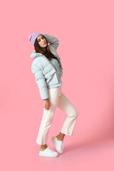 Pretty young woman in stylish warm clothes on color background