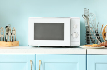 White microwave oven on counter near blue wall - obrazy, fototapety, plakaty