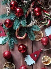 Christmas flatlay with nobilis fir branches in a string bag, christmas decorations of scandinavian ghnomes and lemon slices on a wooden background