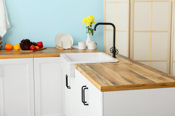 White counters with wooden table top and sink in kitchen