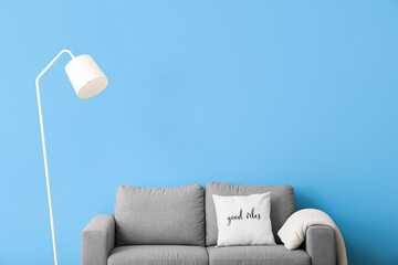 White standing lamp and sofa near blue wall