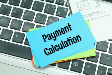 laptop keyboard, receipts and colored paper with the words payment calculation