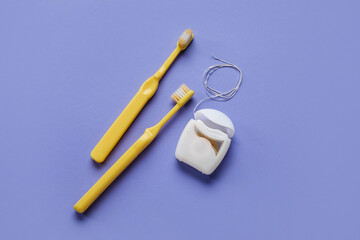 Dental floss and tooth brushes on purple background