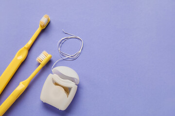 Dental floss and tooth brushes on purple background