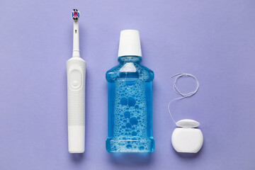 Dental floss, rinse and electric toothbrush on purple background