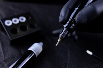 close-up of the hands of the permanent makeup artist of the eyebrows that hold the tattoo machine and you can see the cartridge on it - obrazy, fototapety, plakaty