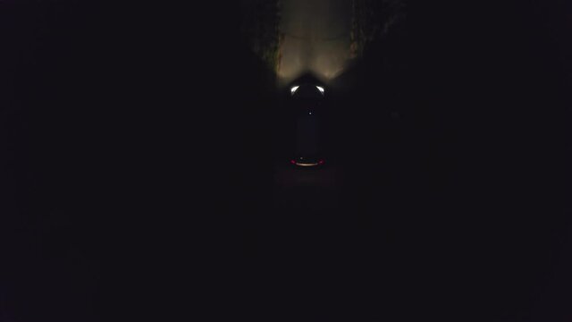 A lone car drives a small road at night with its lights on. Lost in the dark, he looks for a way home, takes the secret away for clothes at night.