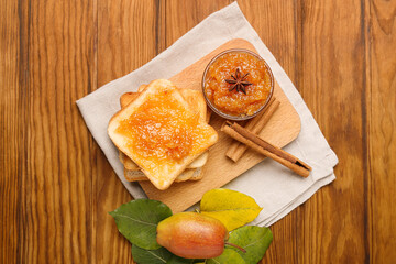 Board with bowl of tasty pear jam and bread on wooden background