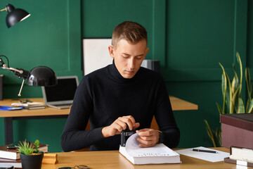 Young male notary public attaching seal to documents in office