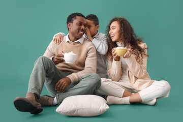 African-American family in winter clothes and with tasty hot chocolate on color background