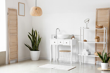 Interior of light bathroom with sink, shelving unit and houseplants