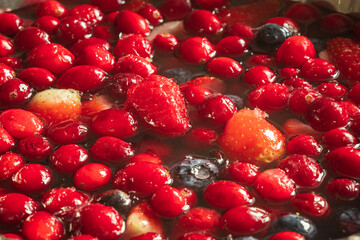 frozen mix strawberries blueberries raspberries and cranberries in water closeup