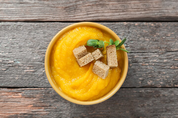 Bowl of tasty pumpkin cream soup on wooden background