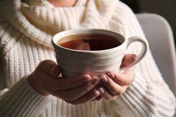 Woman drinking tasty tea in armchair, closeup