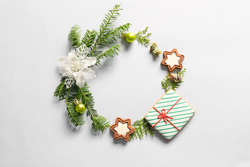 Frame made of fir branches and Christmas cookies on white background