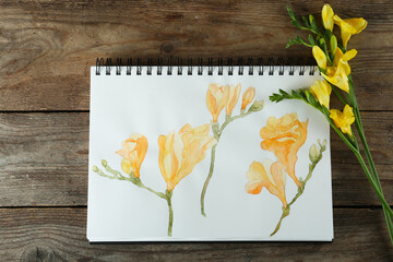 Beautiful drawing of freesia and flowers on wooden table, flat lay