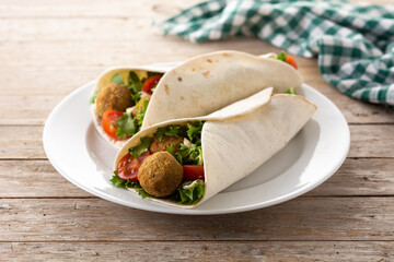 Tortilla wrap with falafel and vegetables on wooden table