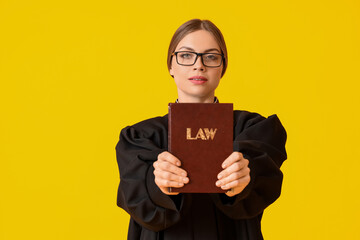 Young female judge with book on color background