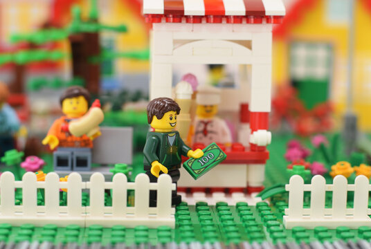 Editorial illustrative image of lego minifiure in park is buying of ice. Street food concept.