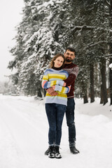 Loving couple in sweaters on a winter walk. Man and woman posing in the frosty forest. Romantic date in winter time.Christmas mood of a young family.Winter lovestory