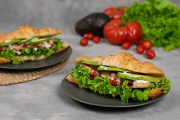 Croissant sandwich with turkey ham, tomatoes, cheese and lettuce salad. Continental style breakfast