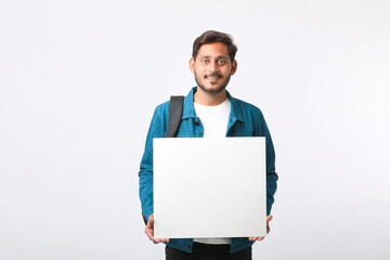 Young indian college student showing blank sign board on white background.