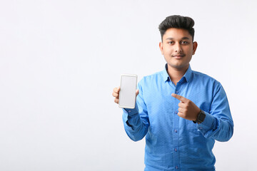 Young indian man showing smartphone screen on white background.