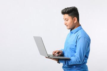 Young indian man using laptop over white background.