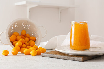 Jar of tasty kumquat jam and fresh fruits on kitchen table