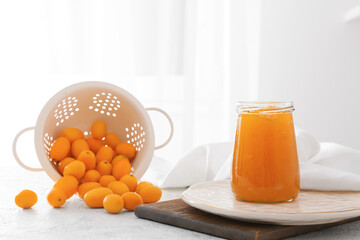 Jar of tasty kumquat jam and fresh fruits on kitchen table