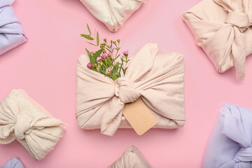 Many gift boxes wrapped in fabric on pink background