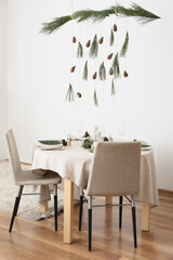 Beautiful table setting with pine cones and fir branches in room