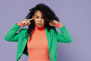 Severe serious concerned young black curly woman 20s years old wears green shirt cover ears with hands fingers do not want to listen isolated on plain pastel light violet background studio portrait.