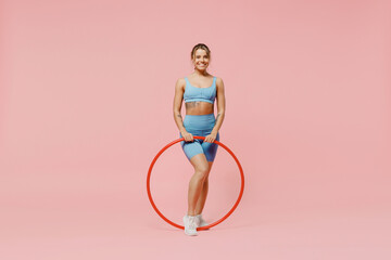 Full size young strong sporty athletic fitness trainer instructor woman wear blue tracksuit spend time in home gym use hula hoop isolated on pastel plain light pink background. Workout sport concept.