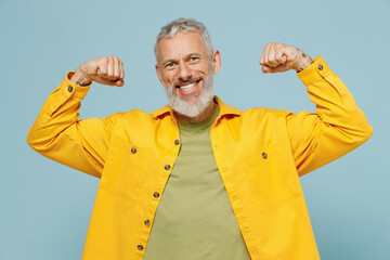 Elderly gray-haired mustache bearded man 50s in yellow shirt showing biceps muscles on hand...