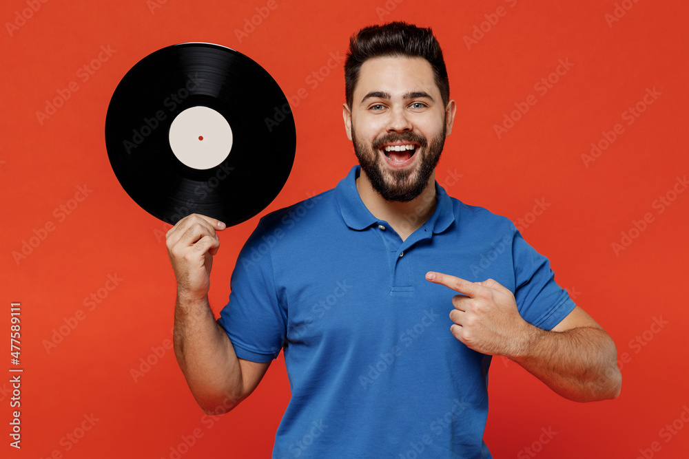 Poster Young excited happy satisfied amazed cool fun man 20s in basic blue t-shirt point finger on hold retro vintage music plate isolated on plain orange background studio portrait People lifestyle concept