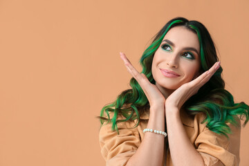 Beautiful young woman with unusual green hair on color background