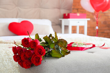 Beautiful red roses on bench in room decorated for Valentine's Day, closeup