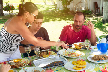 Group of friends and family members enjoying outdoors, having dinner together in nature